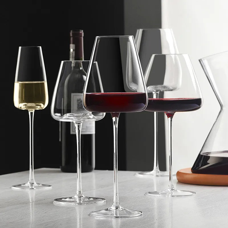 Flera vinglas med rött och vitt vin, en vinflaska och en karaff på ett ljust bord 5