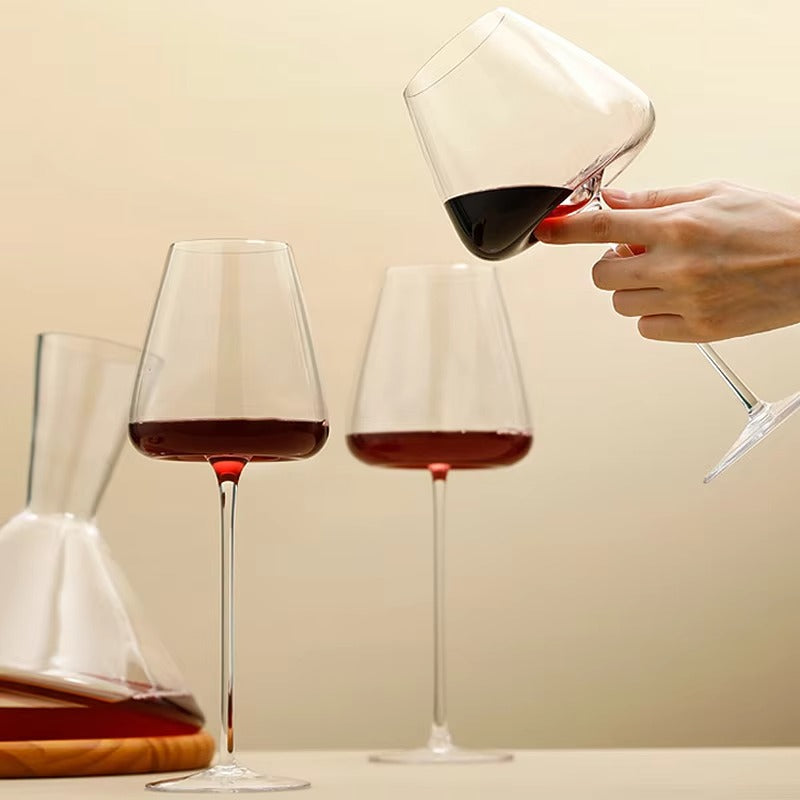 En hand lutar ett vinglas med rödvin vid två stående glas och en karaff 9
