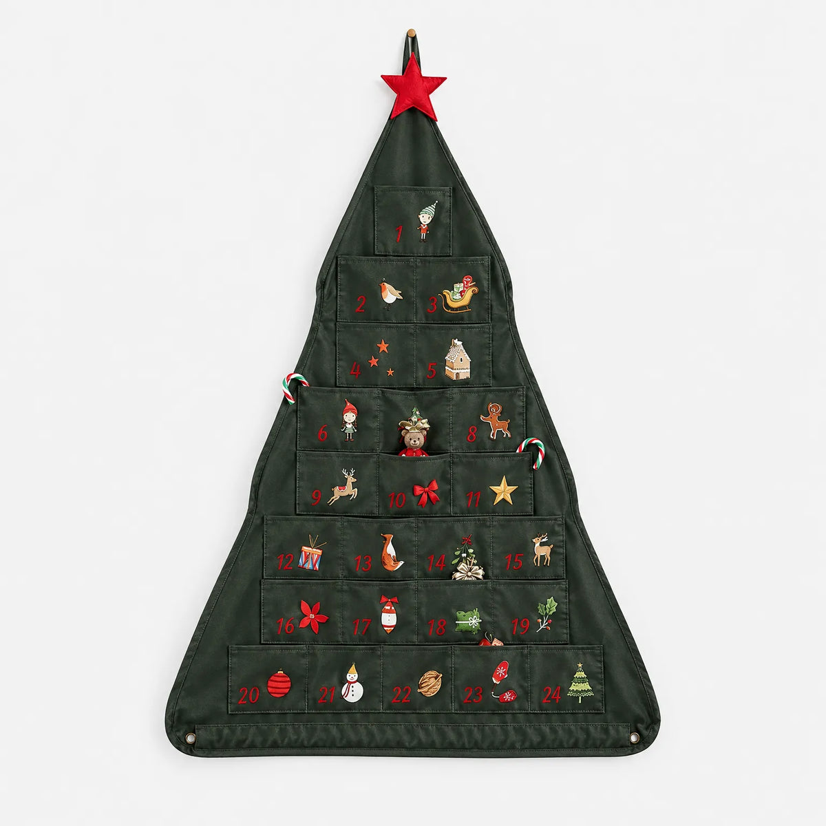 Julkalendern i grön tyg med 24 fickor och tryckta julmotiv, sedd framifrån mot vit bakgrund med en röd stjärna överst. 2