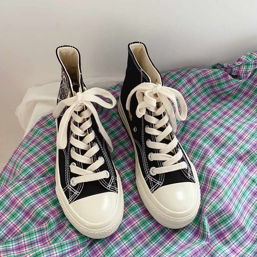 Schwarze High-Top-Sneaker mit weißen Schnürsenkeln auf kariertem Stoff.