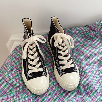 Schwarze High-Top-Sneaker mit weißen Schnürsenkeln auf kariertem Stoff.