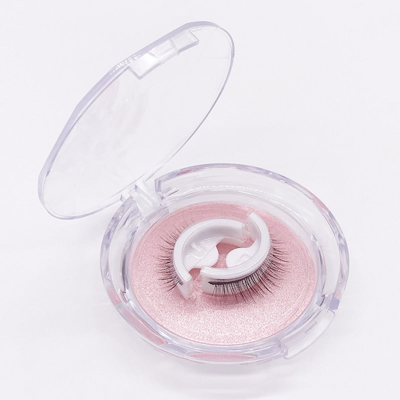 Ett franspar på vit hållare ligger i en öppen, rund genomskinlig ask med rosa glittrande underlag mot vit bakgrund. 6