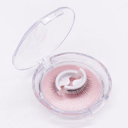 Ett franspar på vit hållare ligger i en öppen, rund genomskinlig ask med rosa glittrande underlag mot vit bakgrund. 6