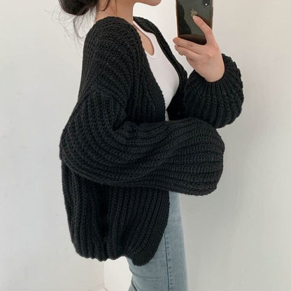 Frau trägt schwarzen Strickcardigan, Oversize, grob gestrickt, modisch, gemütlich, Herbstmode.
