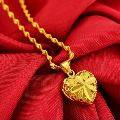 Goldene Herz-Halskette mit Blumenmuster auf rotem Stoff, eleganter Schmuck, Geschenkidee.