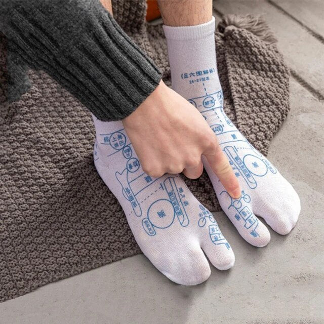 Person trägt weiße Zehensocken mit blauen Akupressur-Mustern auf grauem Teppich.