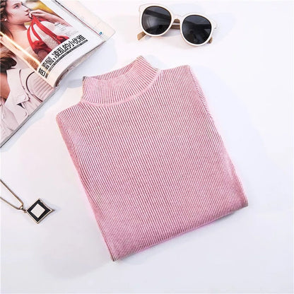 Rosa Rollkragenpullover aus Strick, Damenmode, gefaltet, neben Sonnenbrille und Magazin.