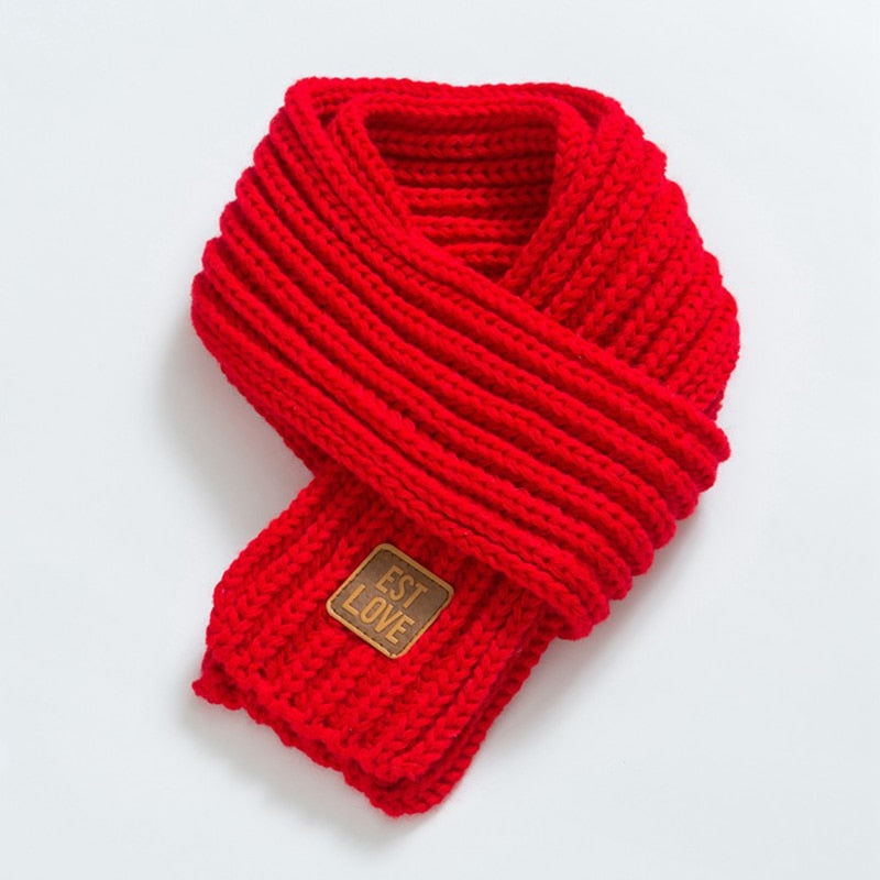 Roter Strickschal aus Wolle mit Etikett, modisches Accessoire für kalte Tage.