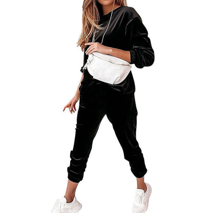 Frau in schwarzem Jogginganzug mit weißer Gürteltasche und weißen Sneakers.