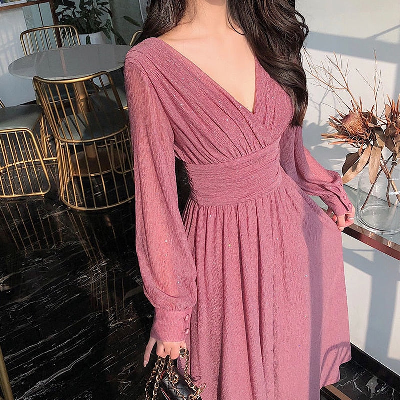 Frau in rosa Abendkleid mit V-Ausschnitt, elegantes Design, langärmlig, modisch.