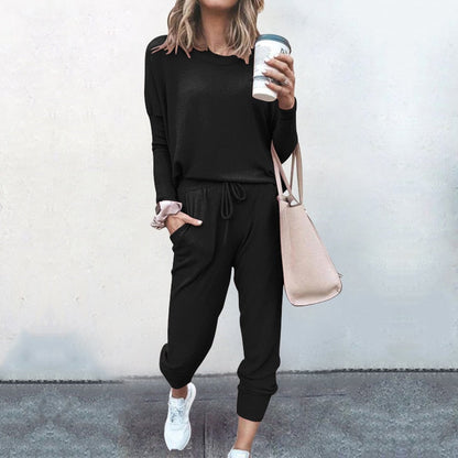 Frau in schwarzem Jogginganzug mit Kaffeebecher und beiger Tasche, lässige Mode.