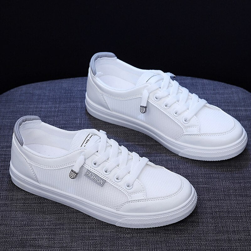 Weiße Sneaker aus Canvas, Unisex, modisch, lässig, mit Schnürsenkeln, auf grauem Hintergrund.