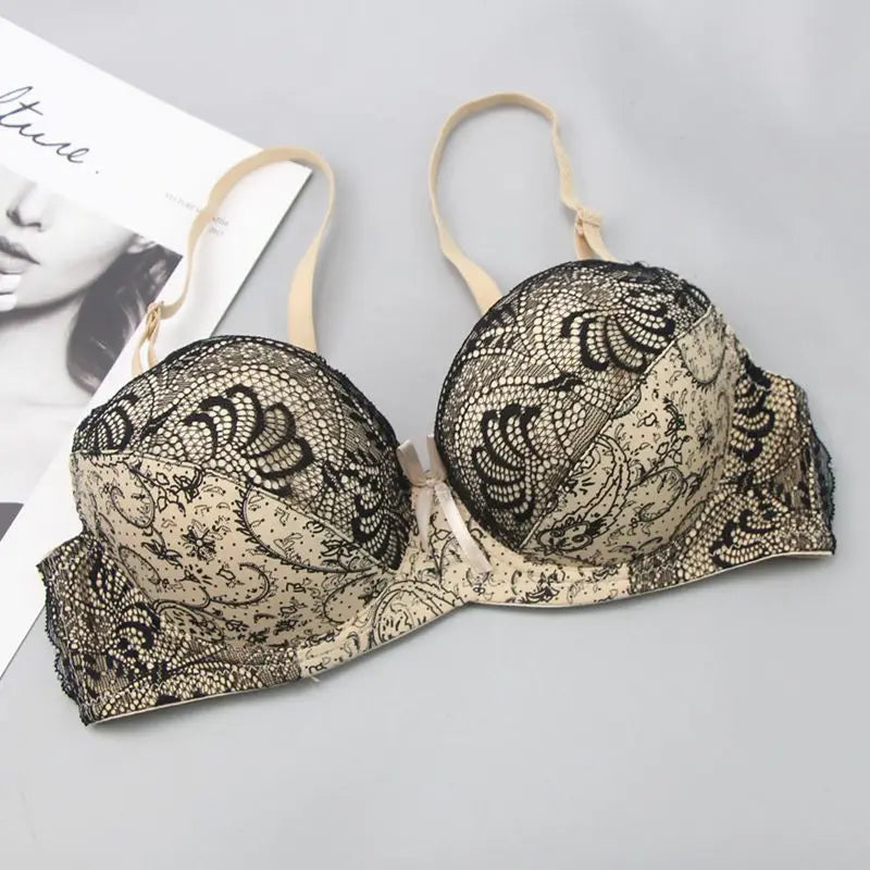 Beiger Spitzen-BH mit schwarzem Muster, verstellbaren Trägern, elegantes Dessous-Design.