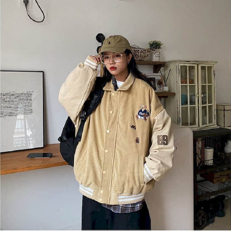 Frau in beiger Collegejacke und Mütze, lässiger Stil, urbaner Look, modische Streetwear.