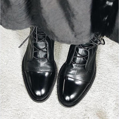 Schwarze Lederstiefel mit Schnürung auf hellem Teppich, elegante Herrenschuhe.