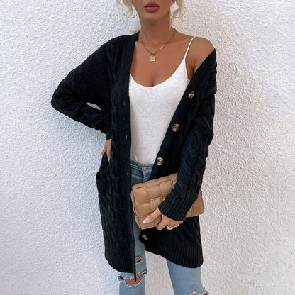 Frau in schwarzem Strickcardigan mit Knöpfen, weißem Top, blauer Jeans und beiger Clutch.