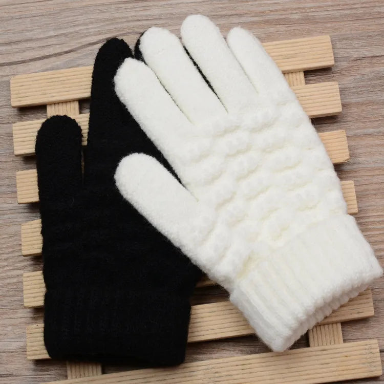 Schwarze und weiße Strickhandschuhe aus Wolle auf Holzunterlage, Wintermode Accessoires.