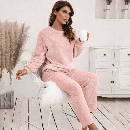 Frau in rosa Fleece-Pyjama mit Tasse, sitzt auf Stuhl, gemütliche Winterkleidung, Wohnzimmer.