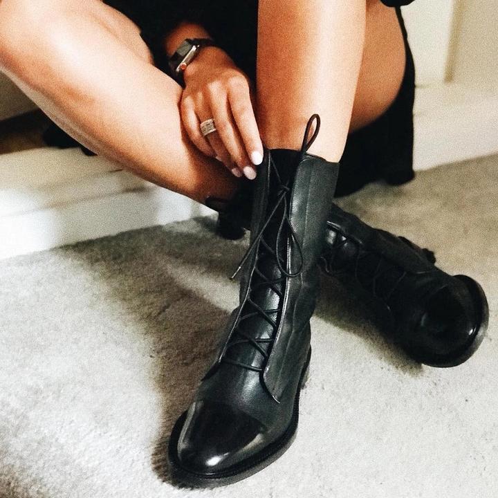 Frau trägt schwarze Lederstiefel mit Schnürung, modisch, elegant, Herbstmode, Damenstiefel.