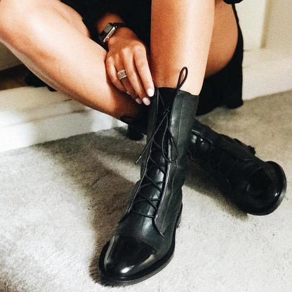 Frau trägt schwarze Lederstiefel mit Schnürung, modisch, elegant, Herbstmode, Damenstiefel.