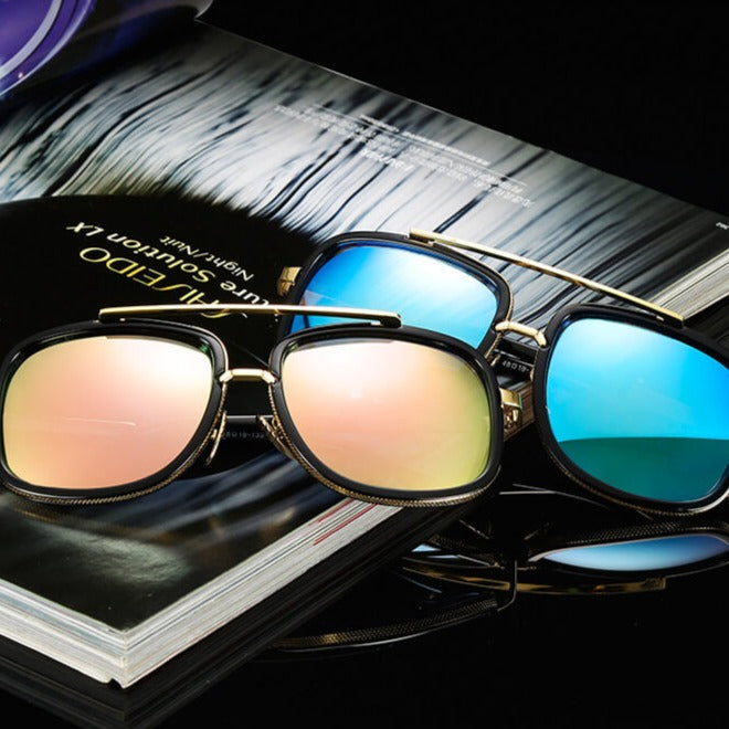 Zwei Sonnenbrillen mit verspiegelten Gläsern auf einem Magazin, modisch, elegant, Unisex-Design.