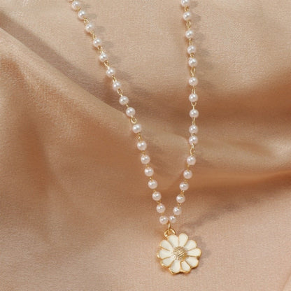 Perlenkette mit weißem Blumenanhänger auf beigem Stoff, eleganter Schmuck für Damen.