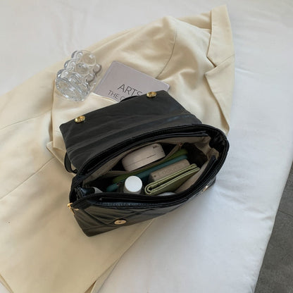 Schwarze Lederhandtasche mit Inhalt auf beigem Mantel, modernes Design, Damenmode.