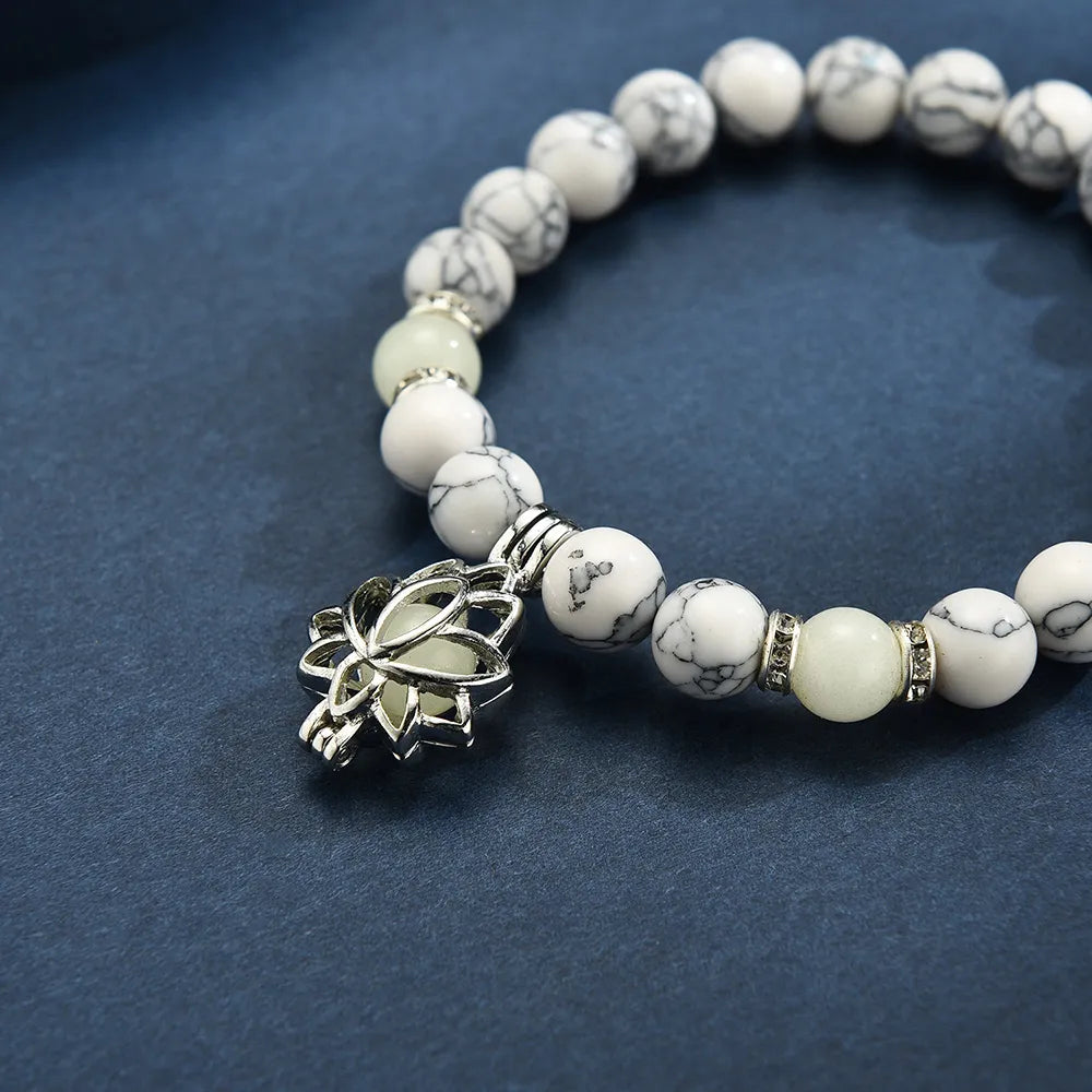 Armband aus weißen Marmorperlen mit silbernem Lotus-Anhänger auf blauem Hintergrund.