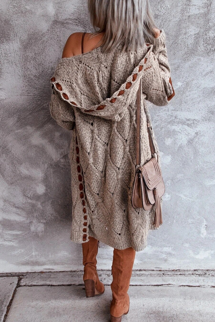 Frau in beigem Strickmantel mit Tasche und Stiefeln, modisch, Herbstmode, Rückansicht.