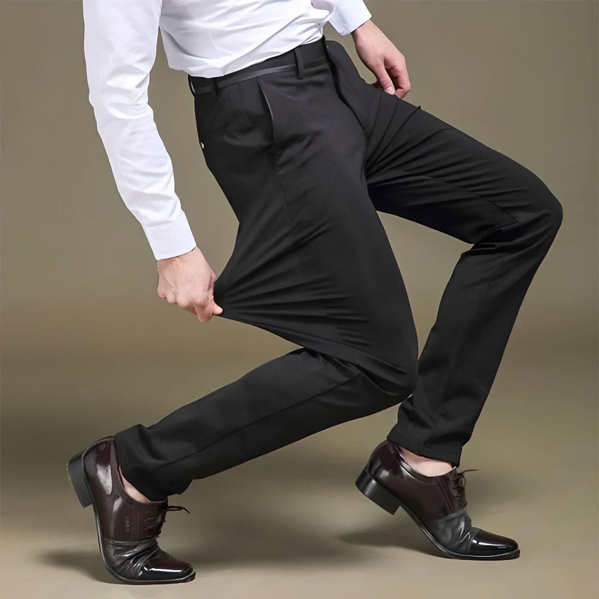 Mann in schwarzer Stretchhose, weißem Hemd, braunen Lederschuhen, zeigt Flexibilität der Hose.
