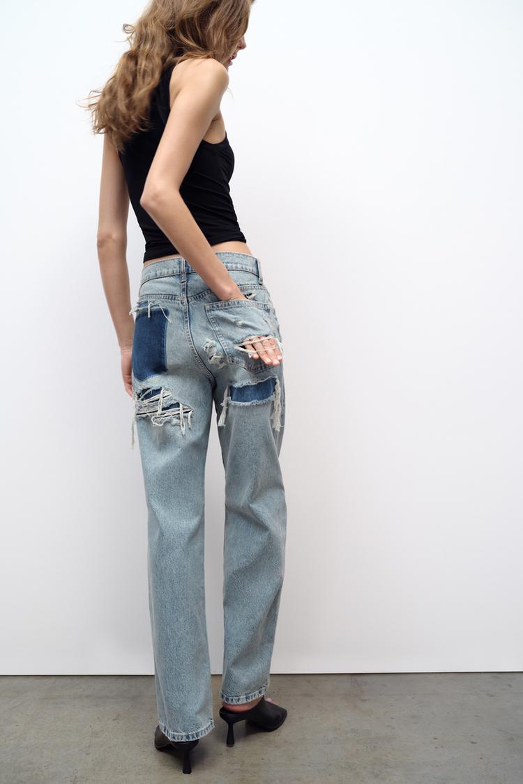 Frau in zerrissener Jeans und schwarzem Top, Rückansicht, modische Damenbekleidung.