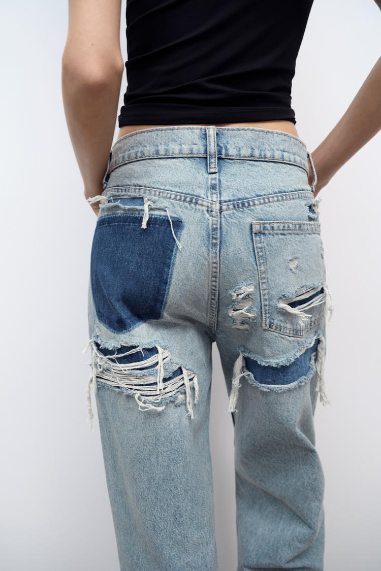 Frau in zerrissener Jeans mit blauen Patches, Rückansicht, modische Damenbekleidung.