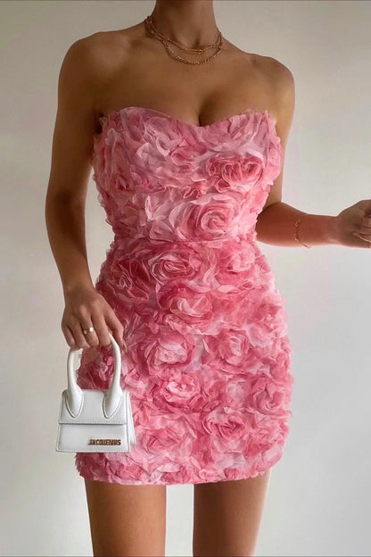 Frau im rosa Blumenkleid mit weißer Mini-Handtasche, elegantes Abendoutfit.