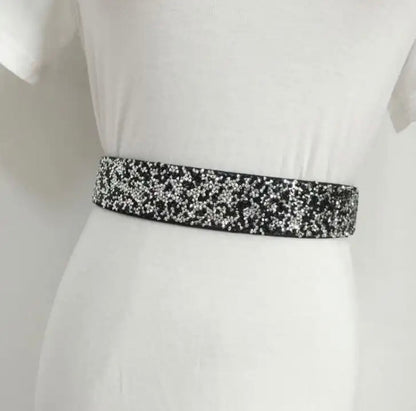 Schwarzer Pailletten-Gürtel auf weißem Kleid, modisches Accessoire, glänzend, elegant.
