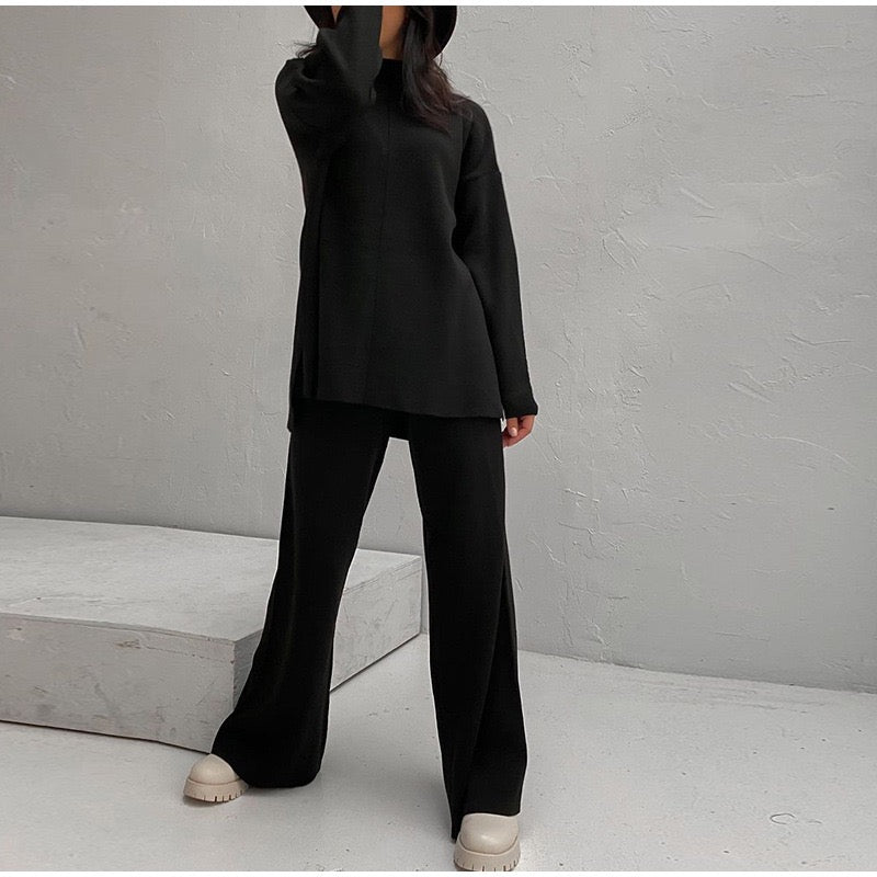Frau in schwarzem Oversize-Pullover und Hose, beige Schuhe, minimalistische Mode.