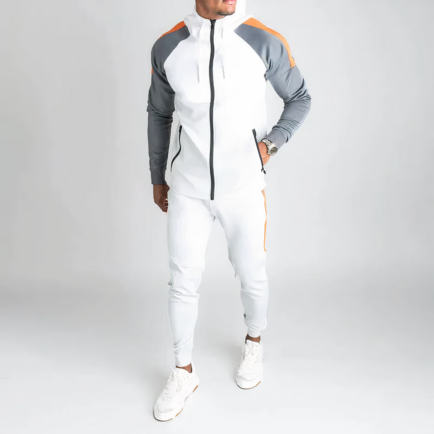 Mann in weißem Trainingsanzug mit grauen und orangefarbenen Akzenten, Sportmode, Fitnessbekleidung.