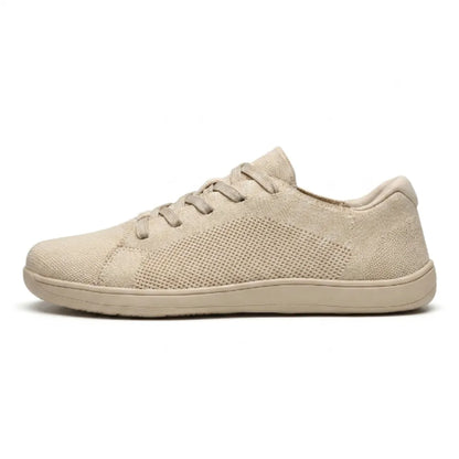 Beige barfotasko i mesh med snörning och platt sula, sedd från sidan mot vit bakgrund. 1