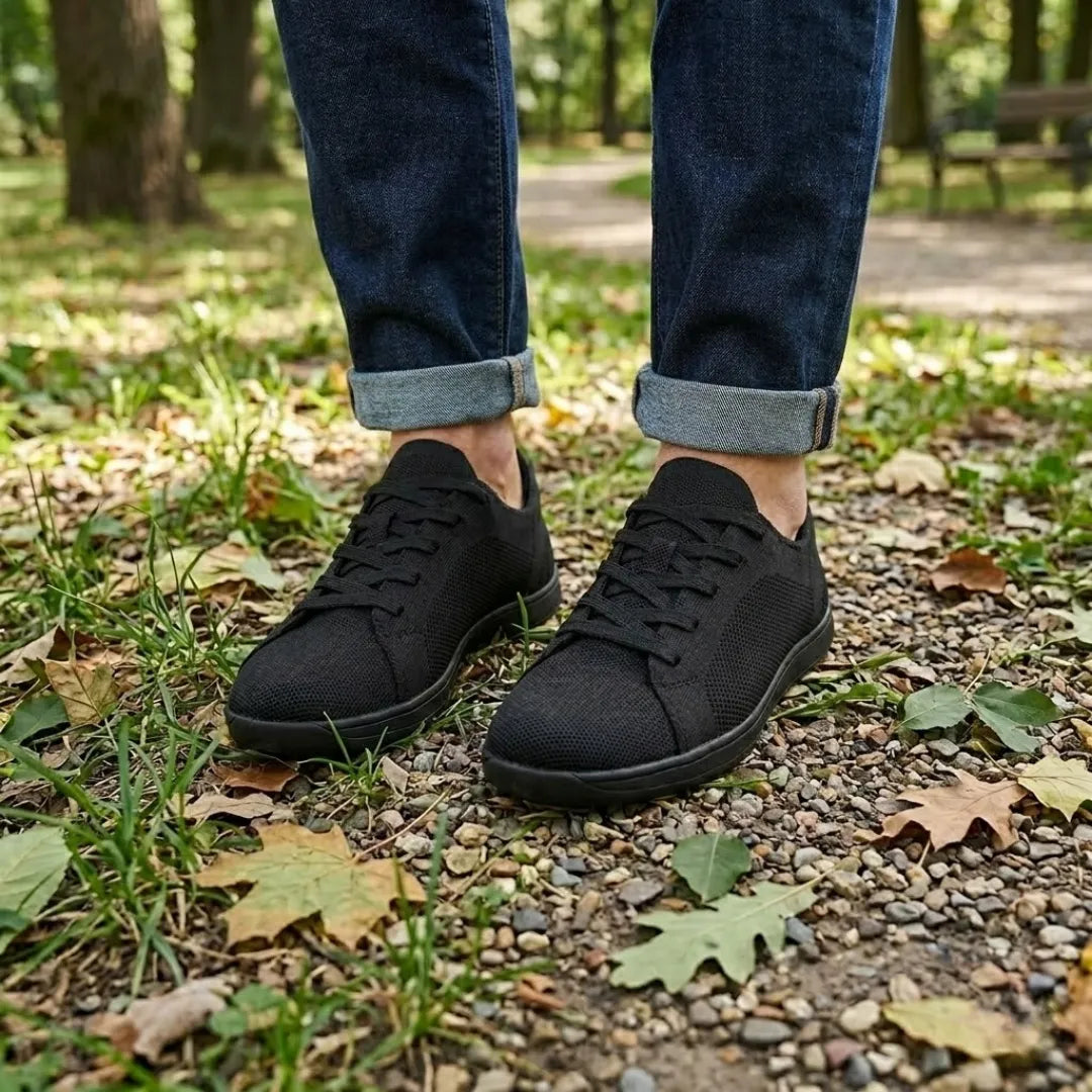 Svarta skor i mesh på en person i mörka jeans med uppvikta ben, på grusig skogsstig. 11