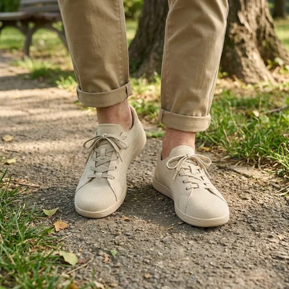 Beige skor i mesh på en person i beige byxor med uppvikta ben, på en parkstig. 2