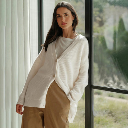 Frau trägt weißen Strick-Cardigan, lässig, modisch, vor Fenster stehend, Herbstmode.