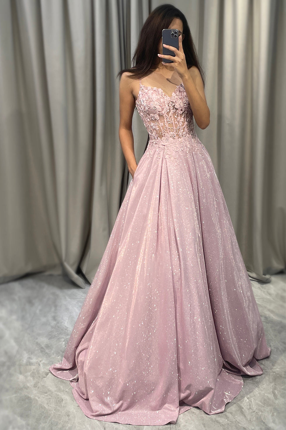 Frau in rosa Abendkleid mit Pailletten, Spaghettiträger, bodenlang, elegantes Design.