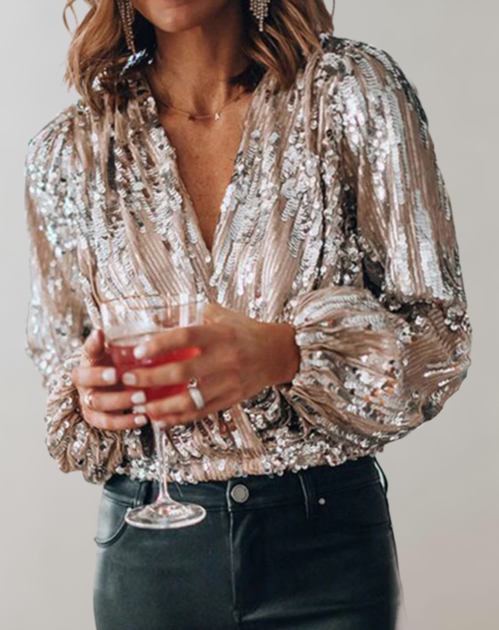 Frau in glitzernder Paillettentop mit Cocktailglas, elegante Abendmode, festliche Kleidung.
