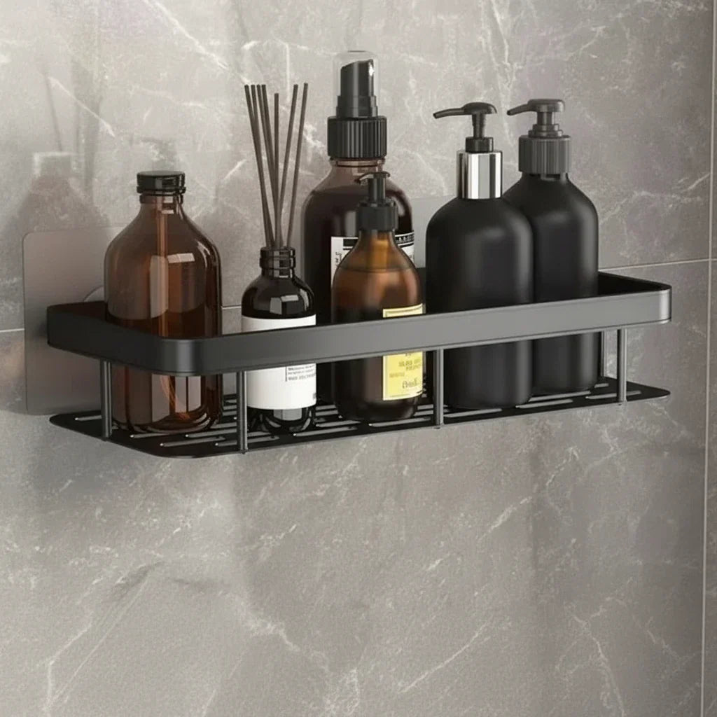 Svart hylla med hålad botten fylld med brunt glas, doftpinnar och svarta pumpflaskor 6