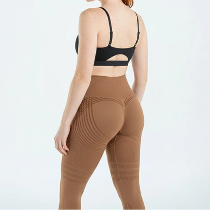 Bruna tights med mönstrade ränder och ribbat midjeband, sedda bakifrån på en modell i svart sport-bh med utskärning. 8