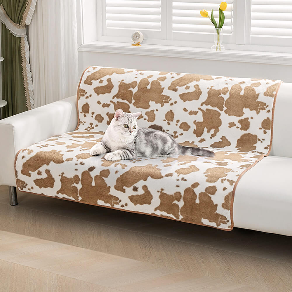 Kuhmuster Plüsch Haustiermatte auf Sofa mit Katze, braun-weiß, gemütlich, modisch, Wohnzimmer.