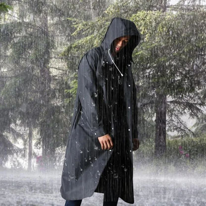 Mann in langer, schwarzer Regenjacke mit Kapuze im Regen stehend, Outdoor-Bekleidung.