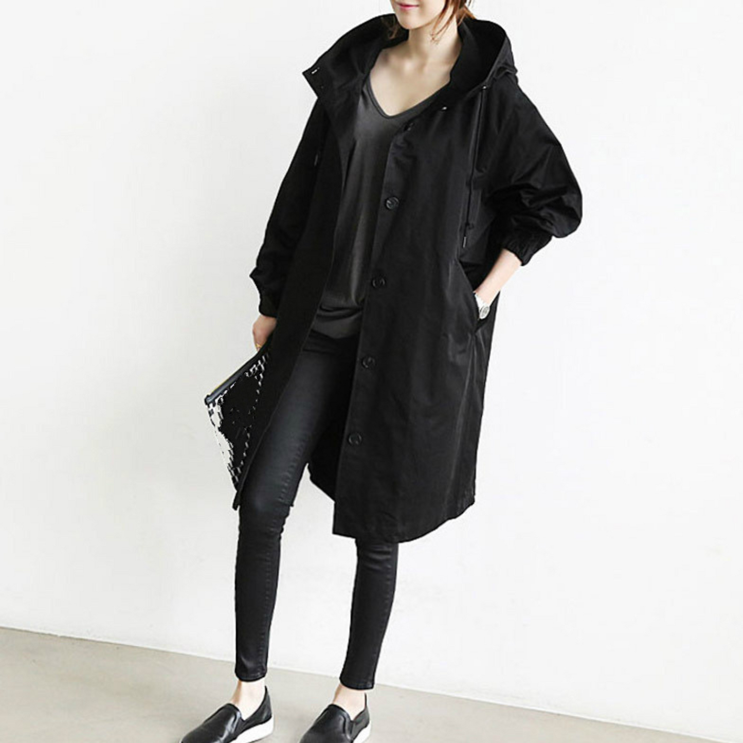Frau in schwarzem Damen-Trenchcoat, lässiger Stil, modische Herbstbekleidung, Kapuze.