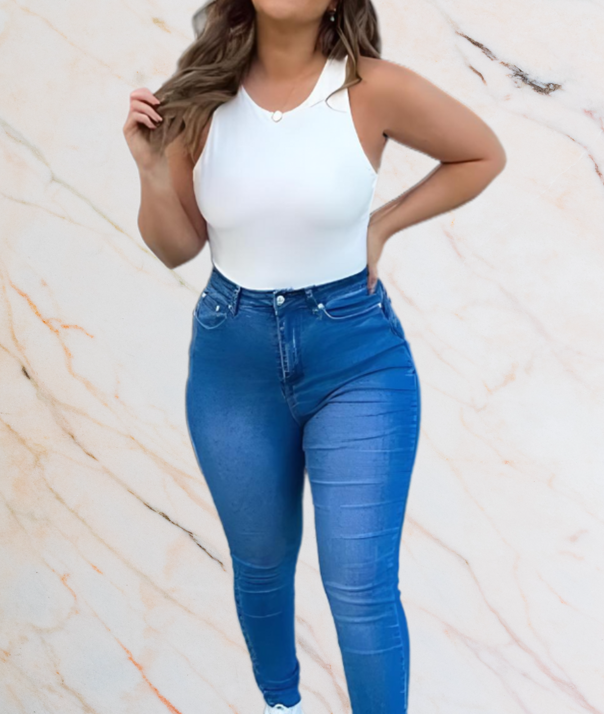 Frau in weißem Tanktop und blauer Jeans vor marmoriertem Hintergrund.