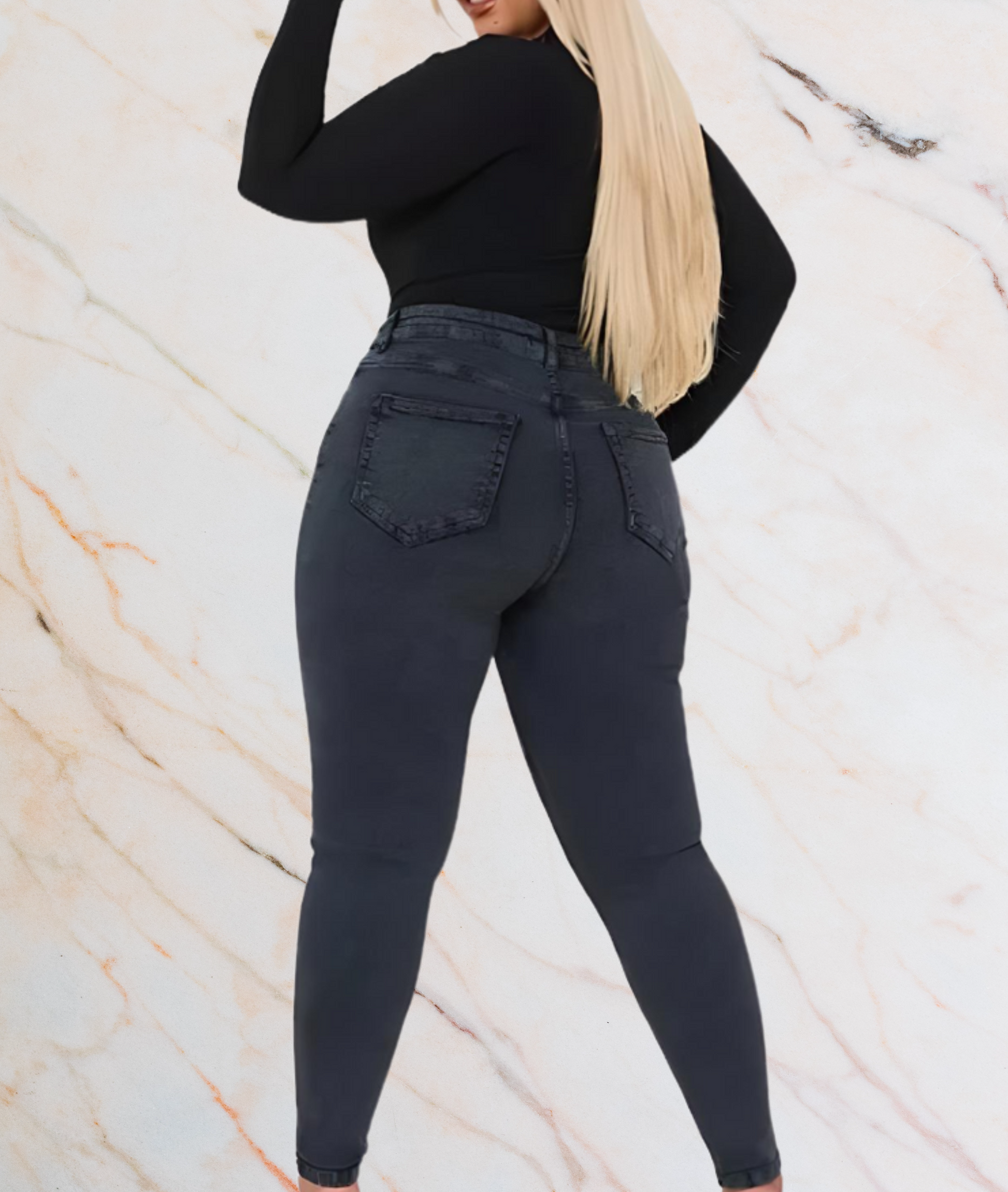 Frau in schwarzer Jeans und schwarzem Oberteil, Rückansicht, blonde Haare, Marmorhintergrund.