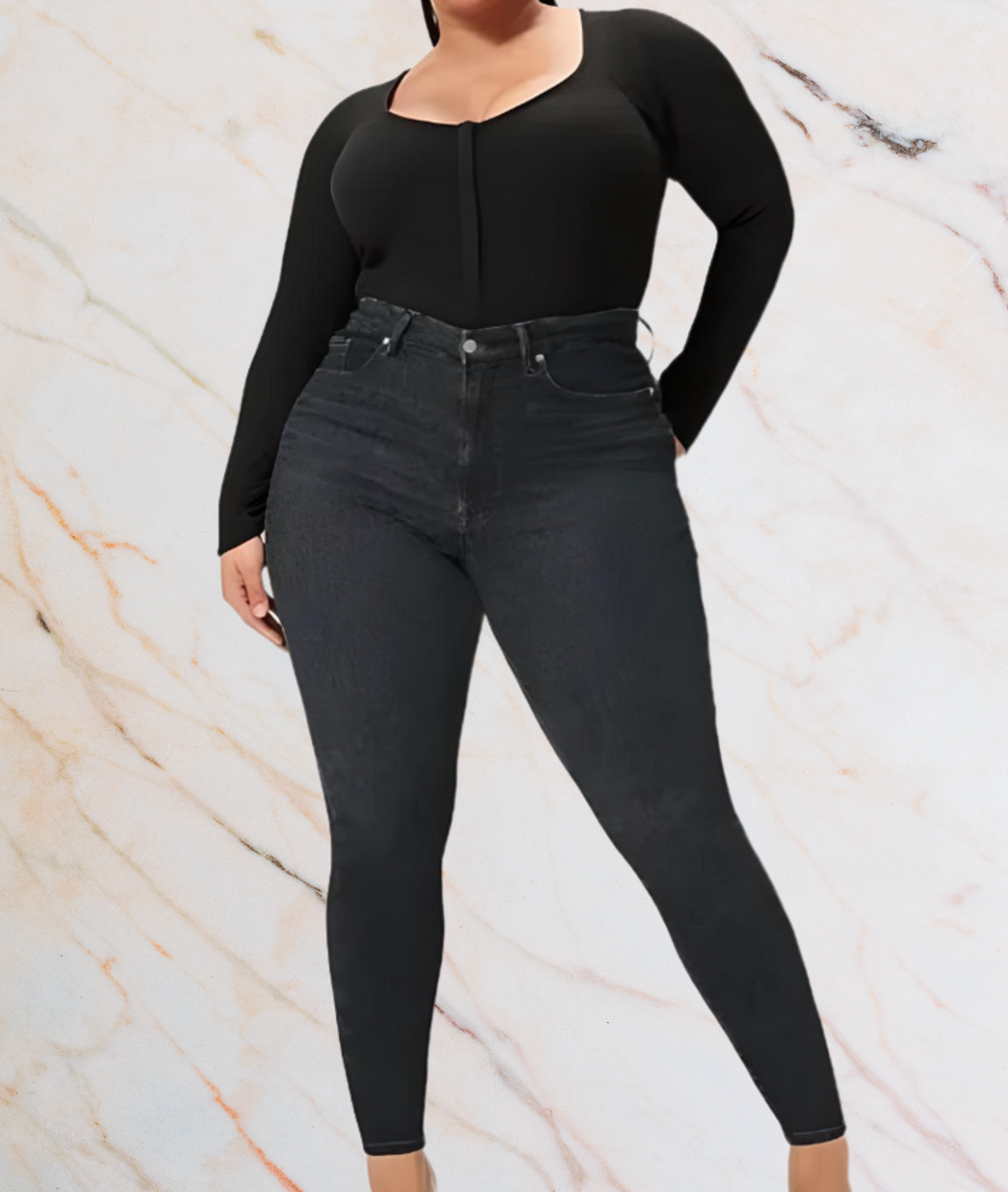 Frau in schwarzem Langarm-Top und Jeans vor marmoriertem Hintergrund.
